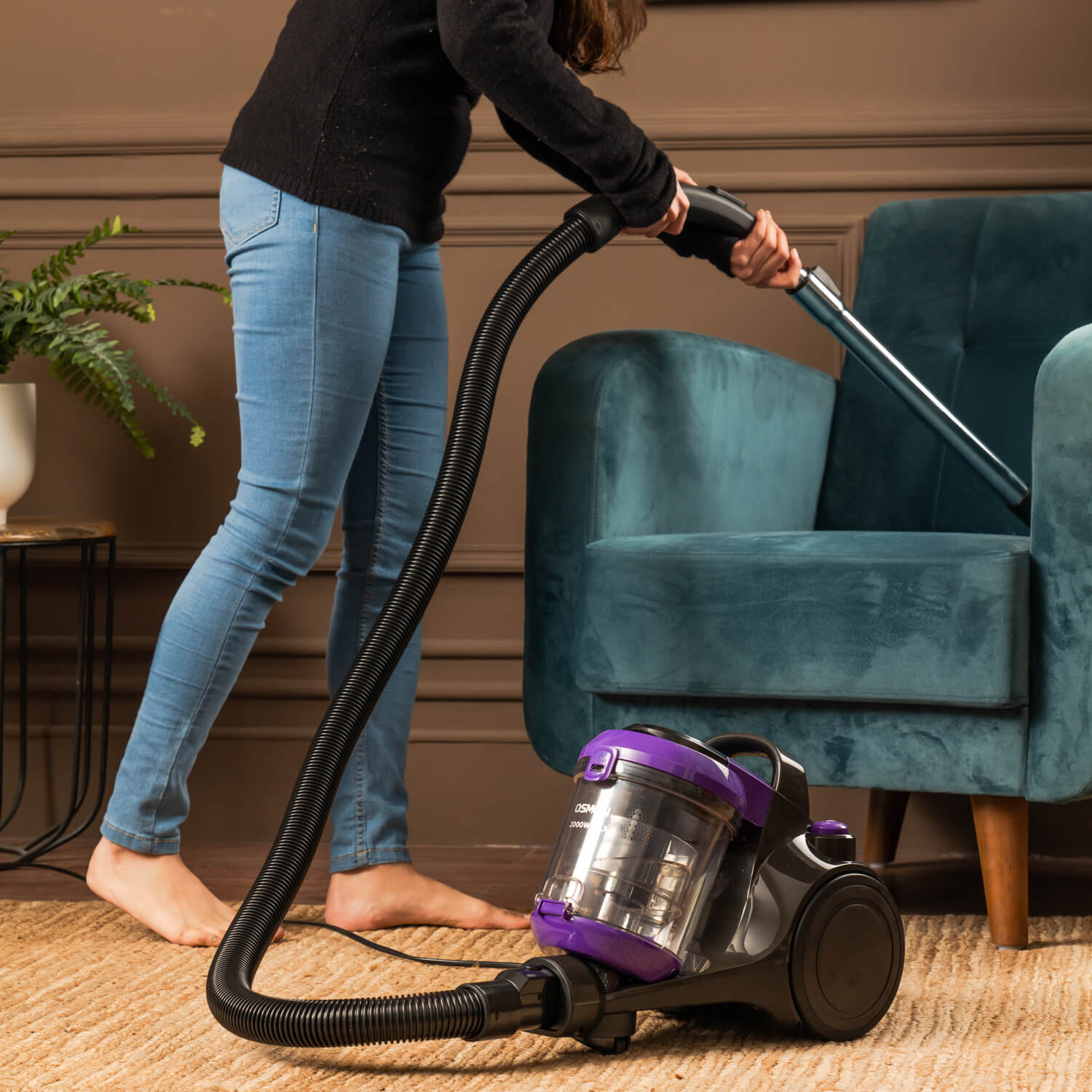 Woman using Osman Purple and black 2000 BL Vacuum cleaner to clean Velvet Sofa