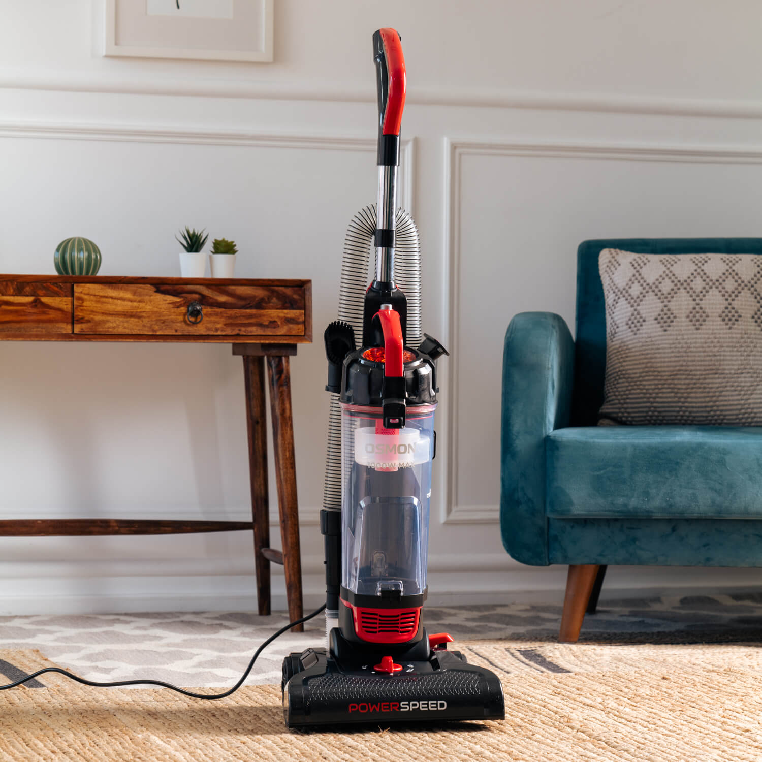 A sleek Red and black vacuum cleaner, the OS 26UBL, stands tall against a backdrop of a clean and tidy living room. Its compact design and HEPA filter make it an ideal choice for effortless cleaning