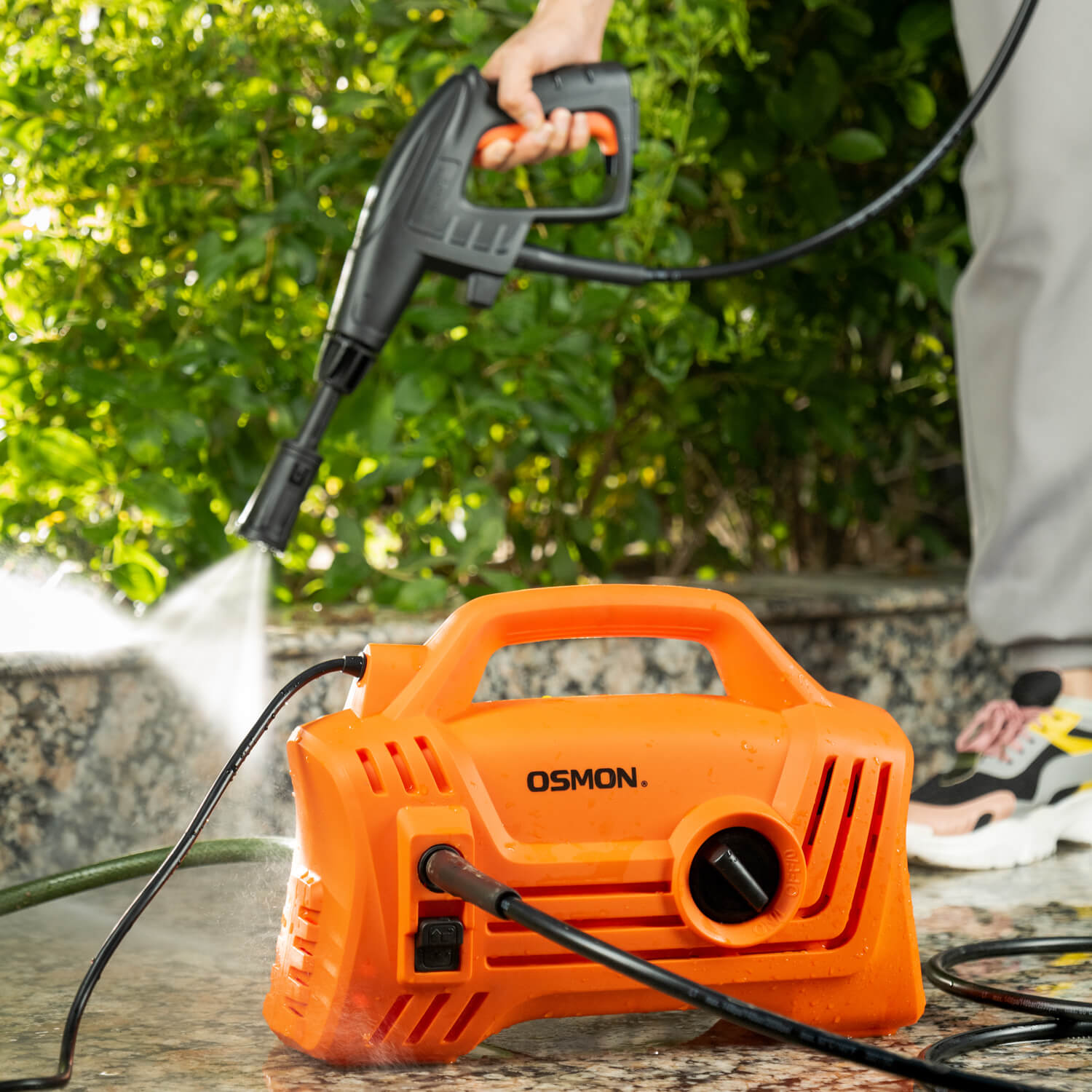 The image showcases the OS PW120 Flow High Pressure Washer, designed for efficient cleaning of cars, bikes, and homes. The pressure washer is featured in a vibrant orange color, adding a touch of style to your cleaning routine