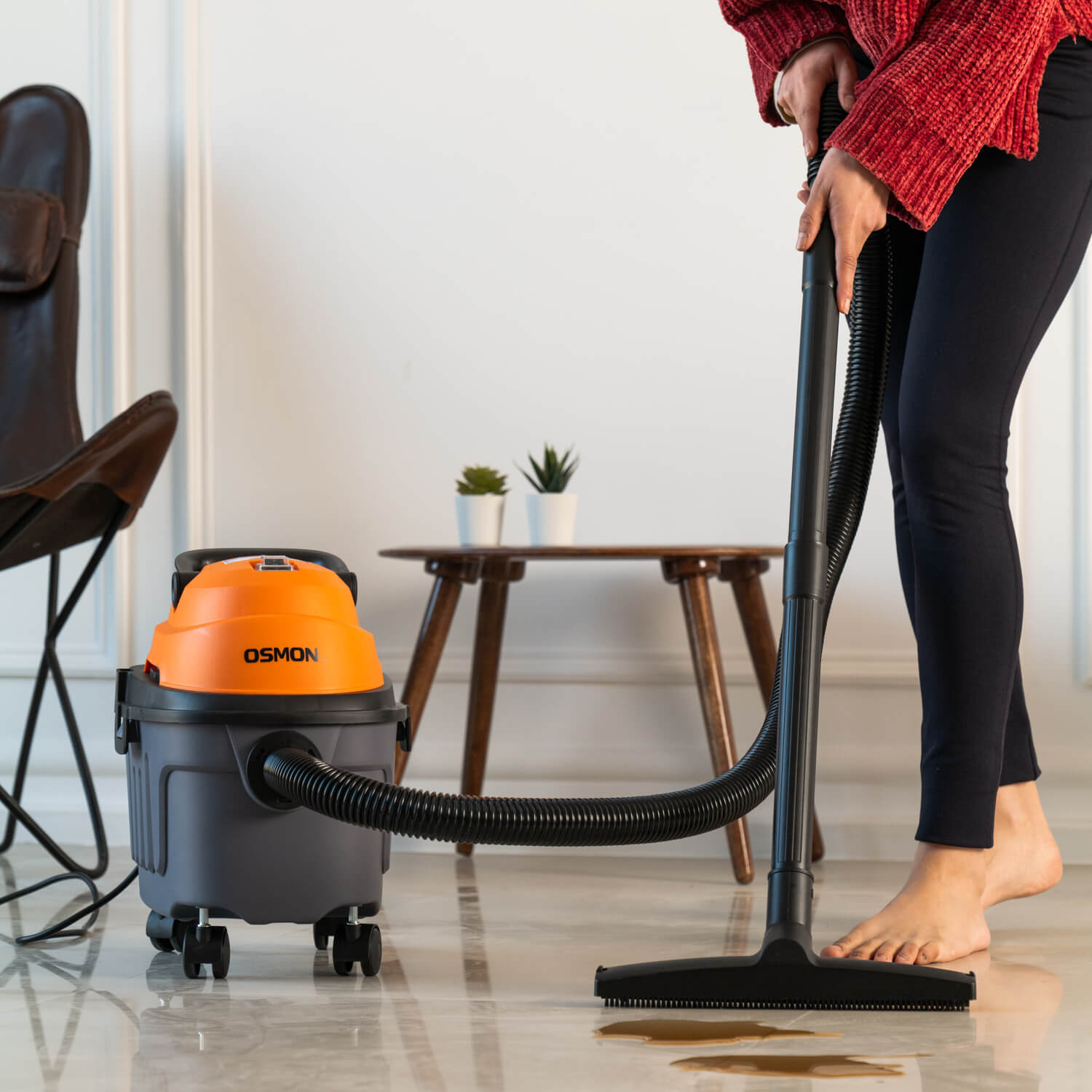 Showcasing the Women standing using the Osmon Wet and dry Vacuum to clean the spill coffee on the floor